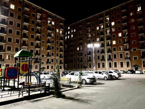 een parkeerplaats met auto's geparkeerd voor hoge gebouwen bij Luxanda Plaza in Samarkand