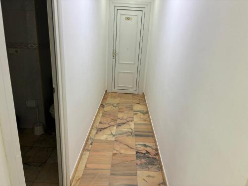 a hallway with a door and a marble floor at Hostal Restaurante La Niña in Palos de la Frontera
