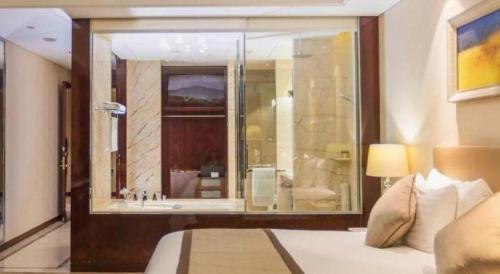 a bedroom with a large window with a bathroom at Dongwu New Century Grand Hotel Huzhou in Huzhou