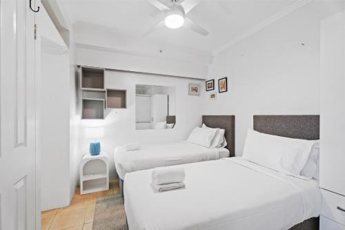 two beds in a room with white walls at Crystal Bay On The Broadwater in Gold Coast