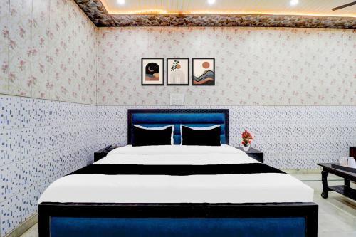 a bedroom with a blue bed with pictures on the wall at Super Hotel O Dehradun Central Railway Junction Formerly Bhagwan Guest House in Dehradun