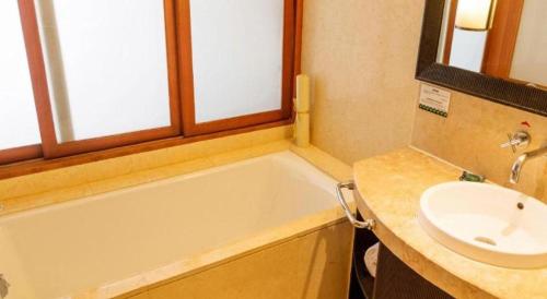 a bathroom with a sink and a bath tub and a sink at Ocean Spring Metropark Hotel Zhuhai in Zhuhai