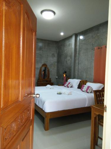 a bedroom with a bed with white sheets at Pottery Street House in Sukhothai