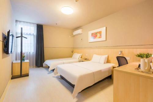 a hotel room with two beds and a television at Magnotel Shanghai Henglong Plaza in Shanghai