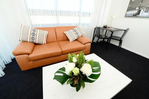 a living room with an orange couch and a table with flowers at Oaks Gladstone Grand Hotel in Gladstone