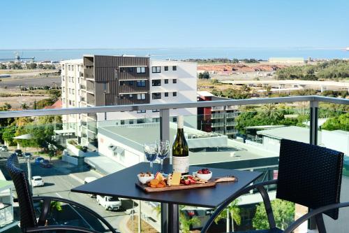 a table with a bottle of wine and glasses on a balcony at Oaks Gladstone Grand Hotel in Gladstone