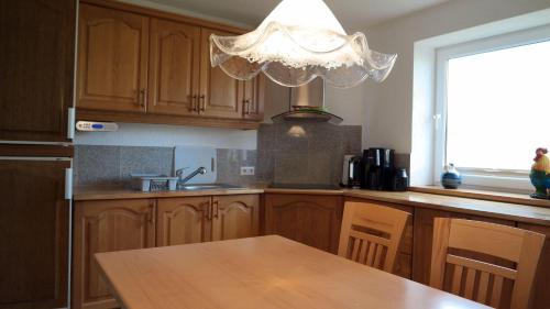 a kitchen with wooden cabinets and a table with a chandelier at Nordsee-1 in Vollerwiek