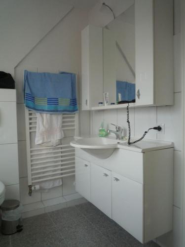 a white bathroom with a sink and a mirror at Nordsee-1 in Vollerwiek