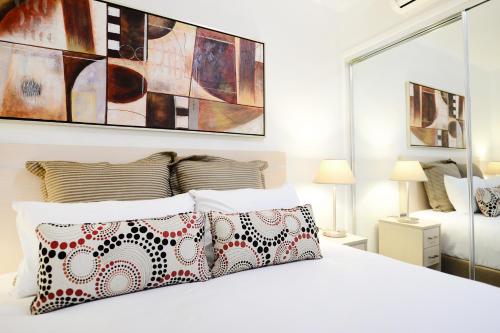 a white bedroom with a white bed with pillows at Oaks Moranbah Suites in Moranbah