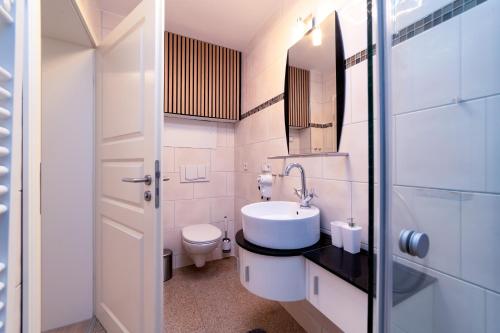 a white bathroom with a sink and a toilet at FeWo Sonnenschein in Sassnitz