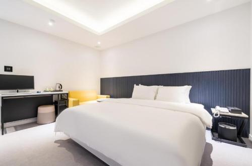 a white bedroom with a large bed and a desk at 호텔 1가 in Suwon