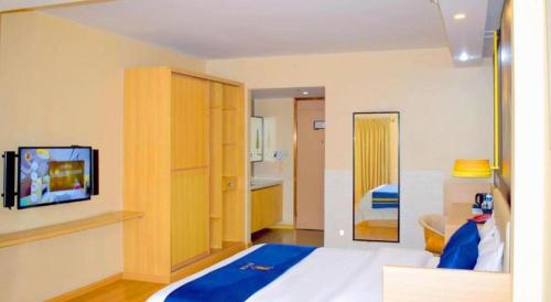 a bedroom with a bed and a tv on a wall at IU Hotel Chengdu High-Tech Zone Longhu Times Street in Chengdu