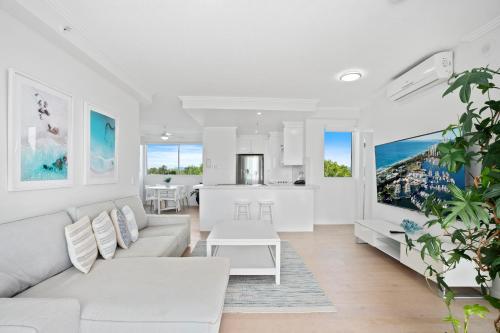a living room with white furniture and a kitchen at Crystal Bay On The Broadwater in Gold Coast