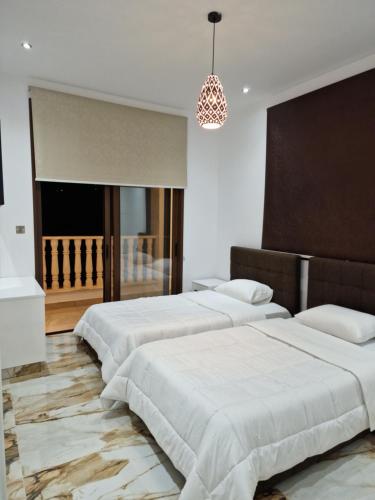 Una fila de cuatro camas en un dormitorio con una lámpara de araña. en Private 5BR Villa with Sunset Rooftop, BBQ zone, Private Pool and Quiet Luxury near sea, en Klorakas