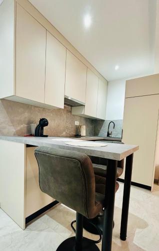 a kitchen with white cabinets and a table and a chair at Studio Amanet in Umag