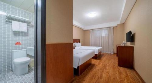 a hotel room with two beds and a bathroom at GreenTree Inn Yantai Xingfu Road Marina Plaza Express Hotel in Yantai
