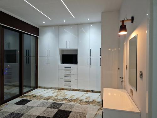 Un baño con muebles blancos, bañera y televisión. en Private 5BR Villa with Sunset Rooftop, BBQ zone, Private Pool and Quiet Luxury near sea, en Klorakas