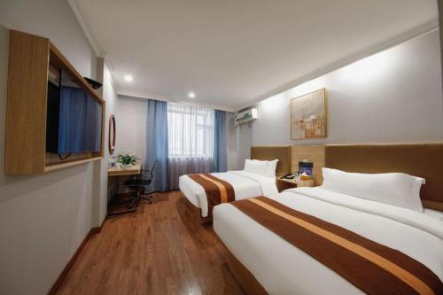 a hotel room with two beds and a television at GreenTree Inn Jiaxing Tongxiang Tudian Express Hotel in Jiaxing