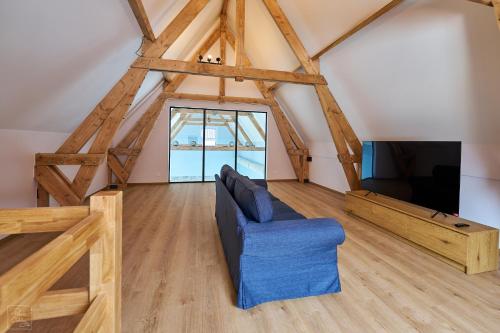a living room with a blue couch and a tv at Les Campanes - Gite 8 personnes avec piscine intérieure et sauna 