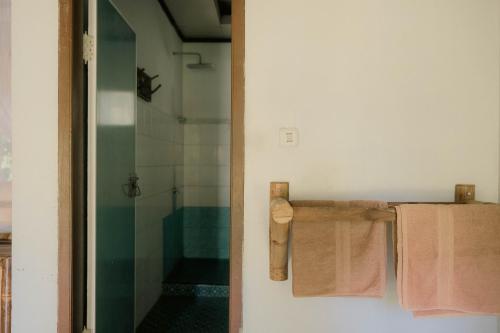 a bathroom with a shower and two towels on a rack at Ecolodge Bukit Lawang in Bukit Lawang