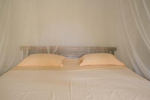 a white bed with two pillows and curtains on it at Ecolodge Bukit Lawang in Bukit Lawang