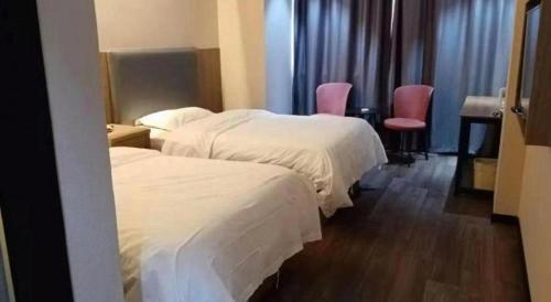 two beds in a hotel room with pink chairs at GreenTree Inn Yancheng Vehicle Administrative office Test Center Express Hotel in Yancheng