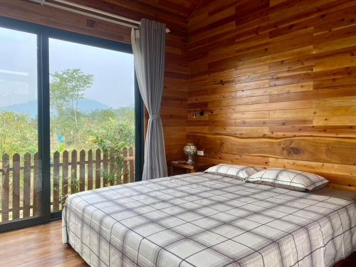 a bedroom with a bed and a large window at Vườn của Nắng Bungalow in Sóc Sơn