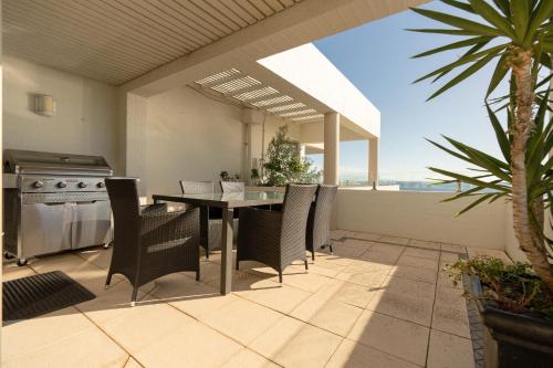 a patio with a table and chairs and a view of the ocean at Beach View Apartment in Cottesloe in Perth