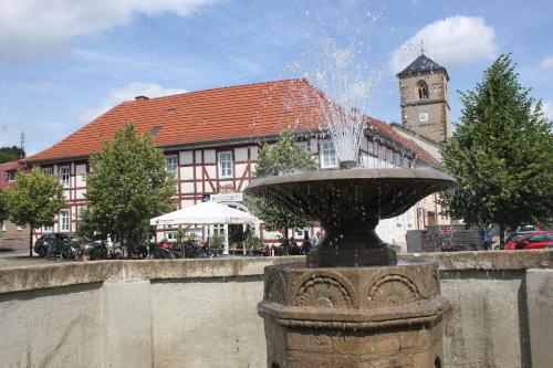 a fountain in front of a building with a clock tower at Hotel Alte Posthalterei in Creuzburg