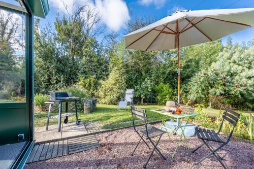 a patio with an umbrella and a table and chairs at Gîte Du Peintre in Challans