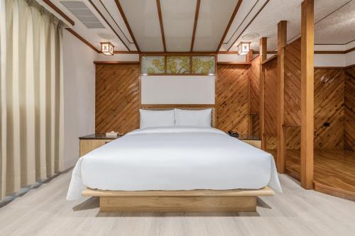 a white bed in a room with wooden walls at Retro Kaohsiung in Kaohsiung