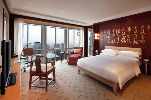 a bedroom with a large bed and a desk and a table at Grand Hyatt Shanghai in Shanghai