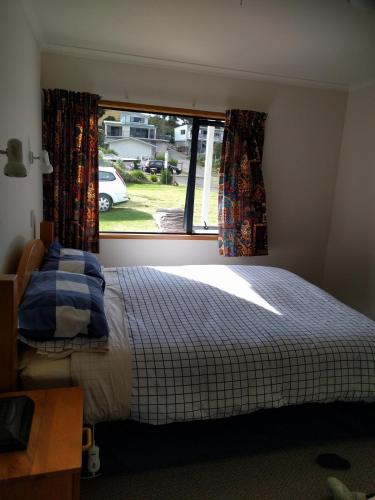 a bedroom with a bed in front of a window at Beachsider upstairs in Whitianga