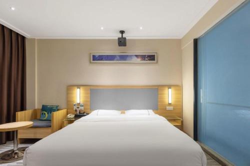 a bedroom with a large white bed and a desk at City Comfort Inn Wuhan High Speed Railway Station in Wuhan