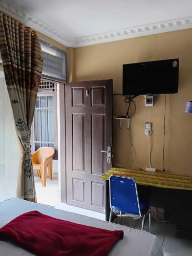 a bedroom with a bed and a tv and a door at Wisma Syariah Rumah Bundo in Padang