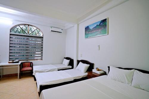 a white room with two beds and a window at Hoalu Rosa Hotel in Ninh Binh