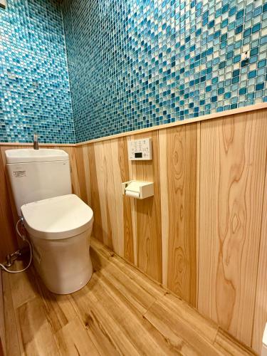 a bathroom with a toilet and a blue tiled wall at Shirakawago Guest House Kei in Shirakawa