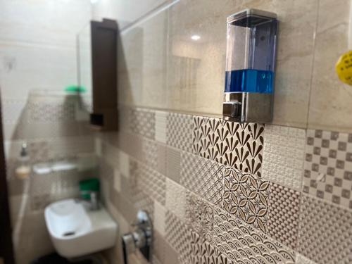 een badkamer met een wastafel en een toilet op een betegelde muur bij Infinity Penthouse with Pool, Sauna, Gym in Rajkot