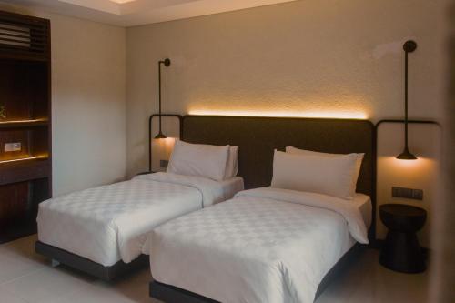 two beds in a hotel room with white sheets at Aruni Bali Jimbaran Boutique Villa in Jimbaran