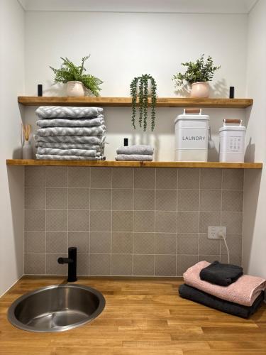 a bathroom with a sink and a shelf with towels at Newly built self-contained guest suite in Ellenbrook in The Vines