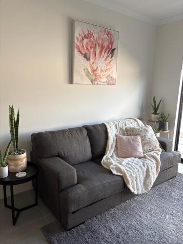 a gray couch in a living room with a flower painting at Newly built self-contained guest suite in Ellenbrook in The Vines