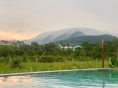 a swimming pool with a mountain in the background at Vườn của Nắng Bungalow in Sóc Sơn