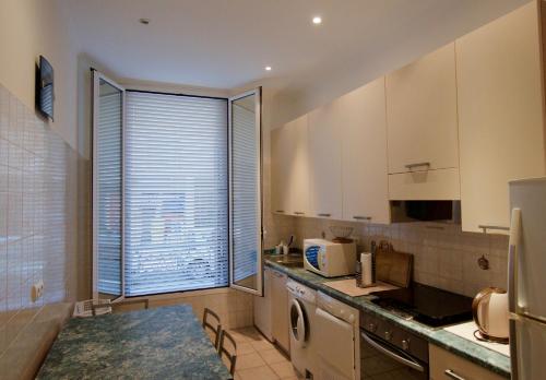 une cuisine avec lave-linge, évier et fenêtre dans l'établissement Appartement les clematites, à Menton