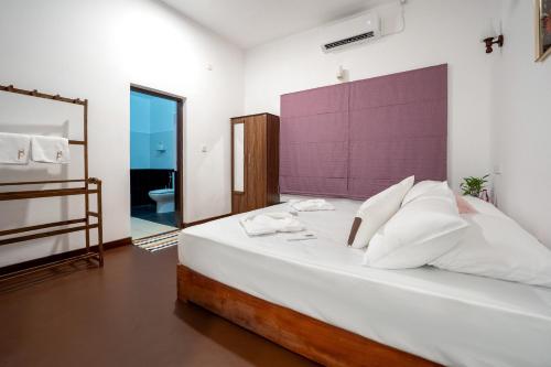 アハンガマにあるThambara Collection Boutique Hotelのベッドルーム(紫色のヘッドボード付きの大きな白いベッド1台付)