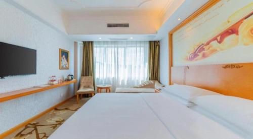 a hotel room with a large bed and a television at Out Sky Hotel in Huizhou