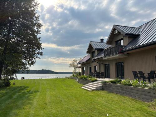 a house with a lawn next to a body of water at Biała Czapla in Augustów