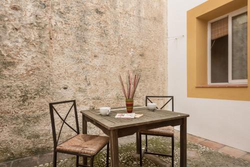 una mesa de madera con 2 sillas y un jarrón. en Apartamento Guzman el Bueno, en Tarifa