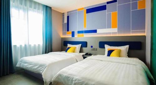 a bedroom with two beds and a painting on the wall at 7 Days Inn Xi'an Railway Station in Xi'an