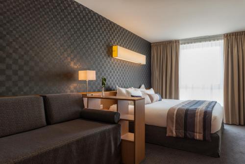 a hotel room with a bed and a couch at Best Western Plus Paris Saclay in Saclay