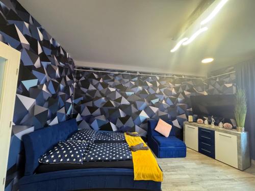 une chambre avec un canapé bleu et un mur géométrique dans l'établissement Kitty Downtown Apartman, à Debrecen